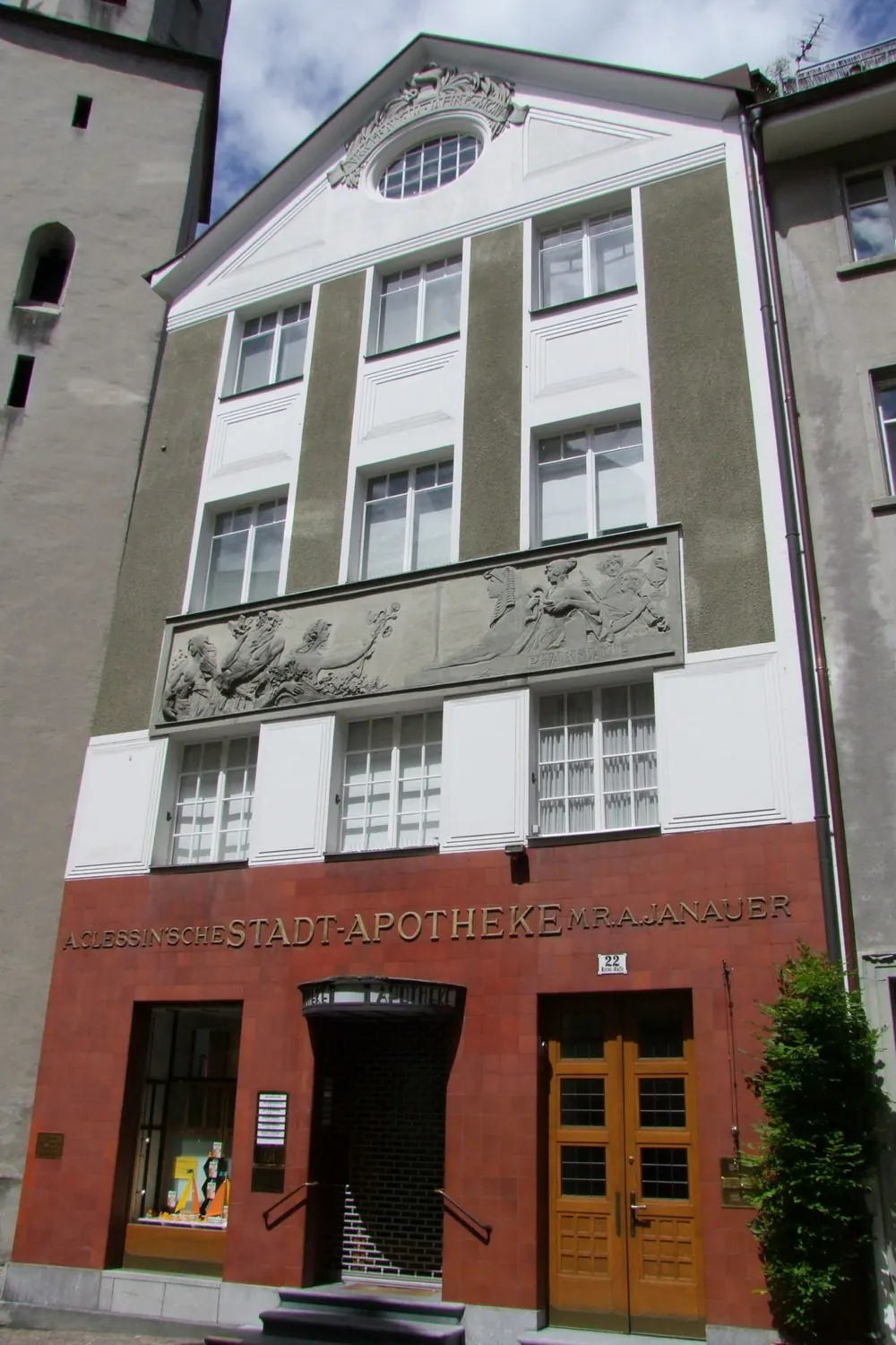 Das Haus der Stadt-Apotheke in der Kreuzgasse von schräg unten, mit Giebel, Fries und rotem Erdgeschoss